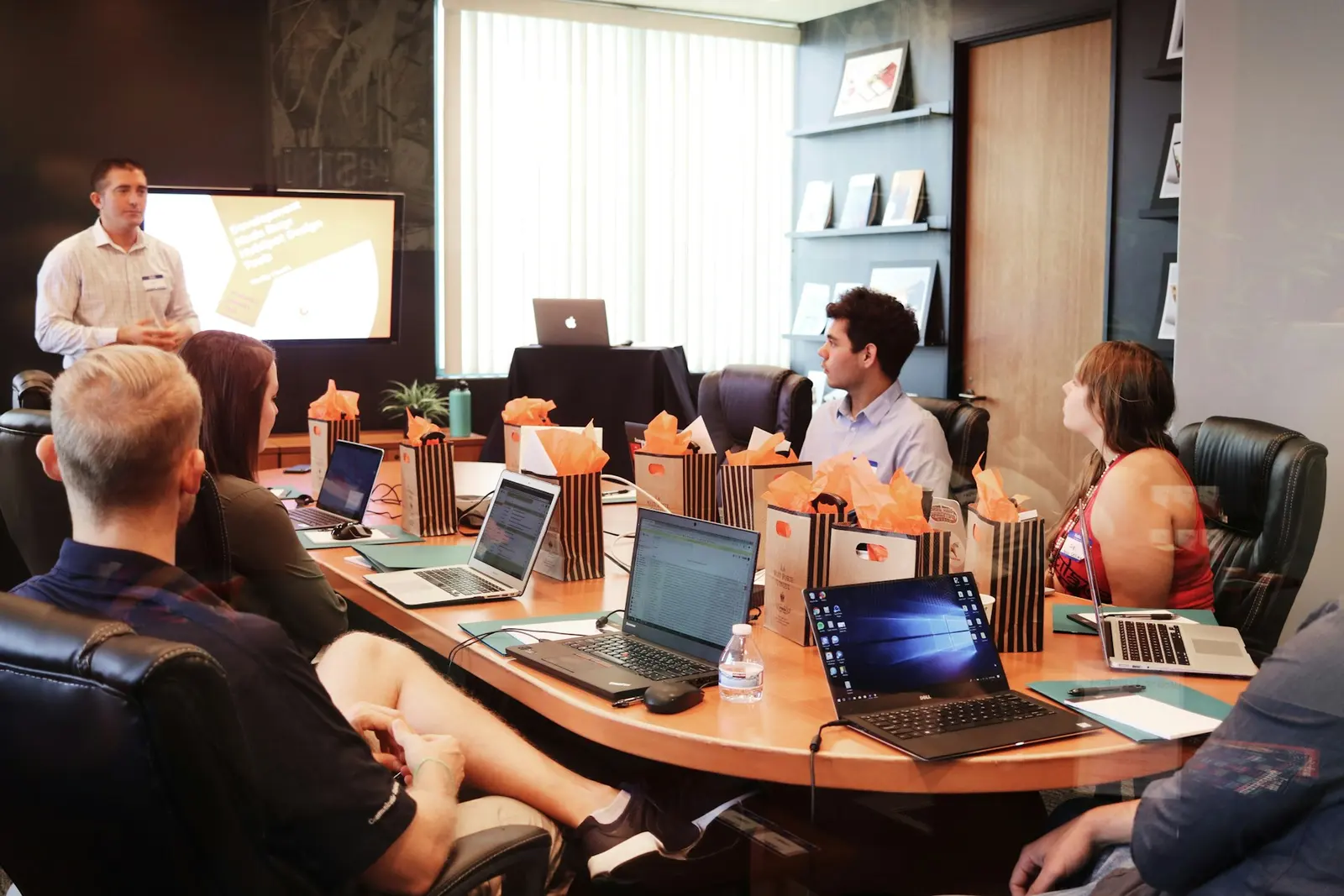 A team in a conference room reviewing a presentation on a wall screen