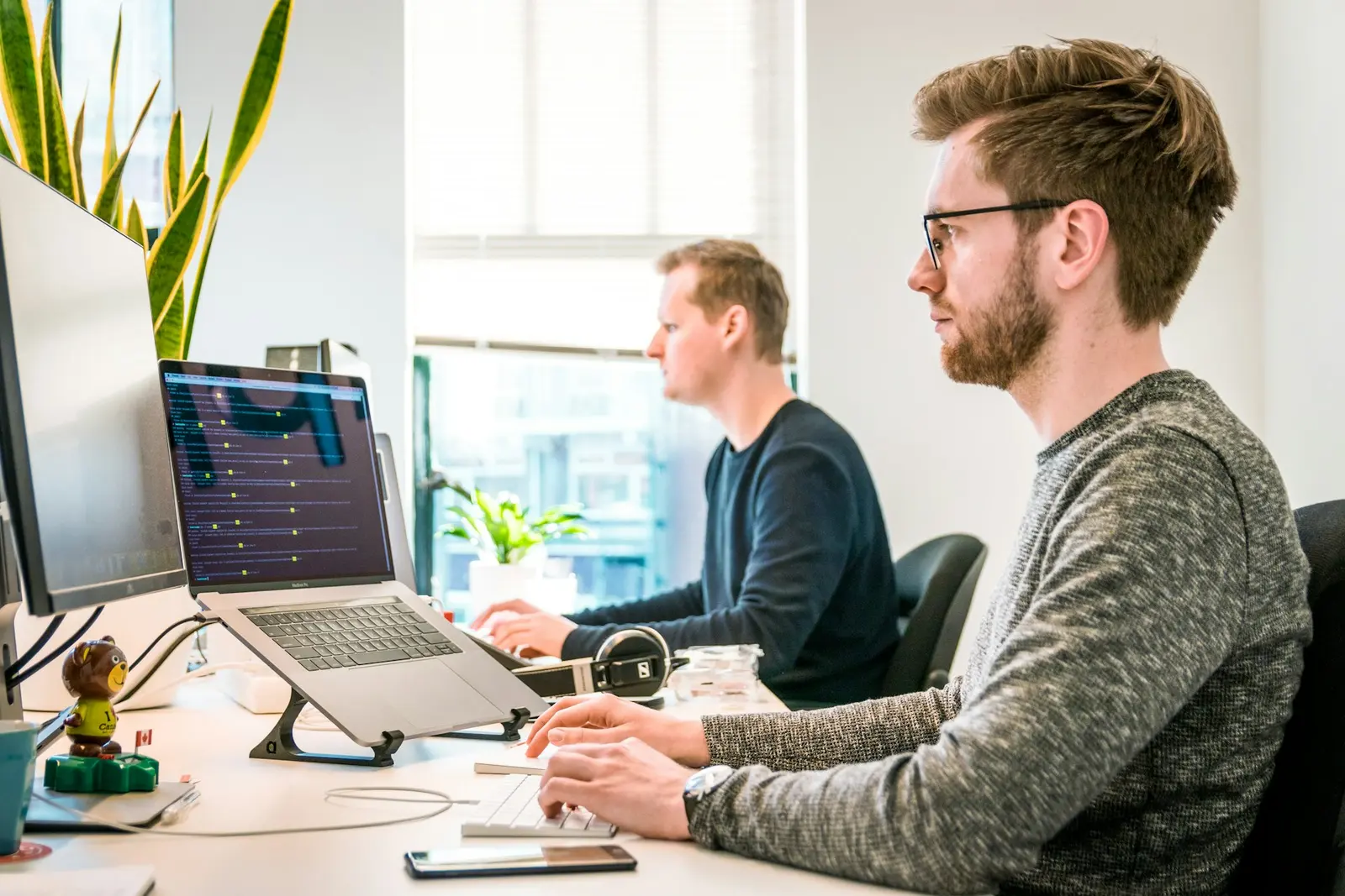 Two engineers working side by side at a bank of monitors
